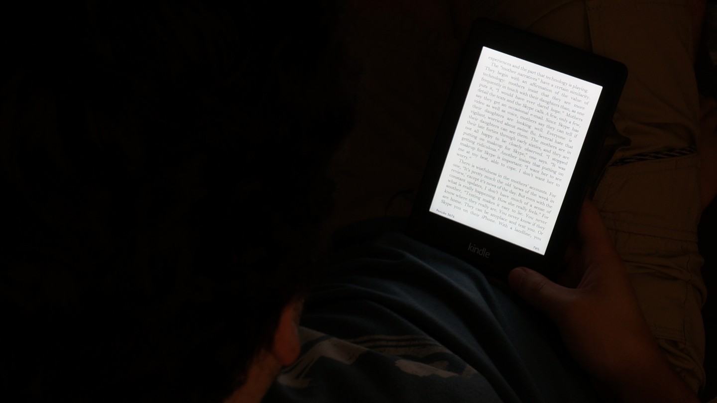 Lendo um livro de boa no escuro, no Kindle Paperwhite com a tela iluminada.