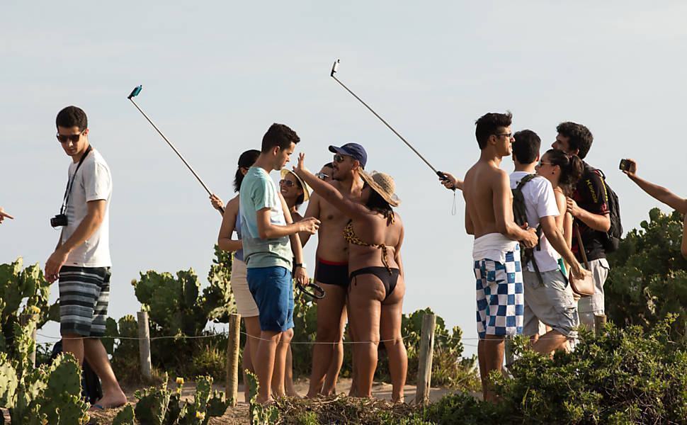 Turistas e cariocas brincando com pau de selfie.