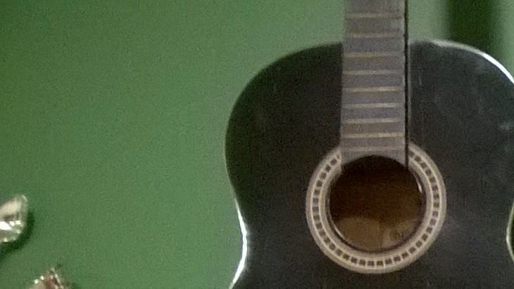 Um violão numa parede verde.