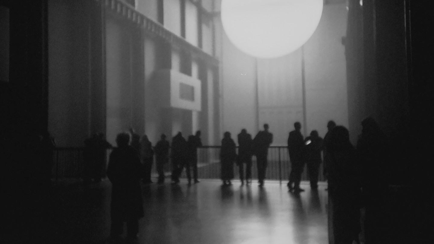 Silhuetas de pessoas em frente a uma espécie de turbina.