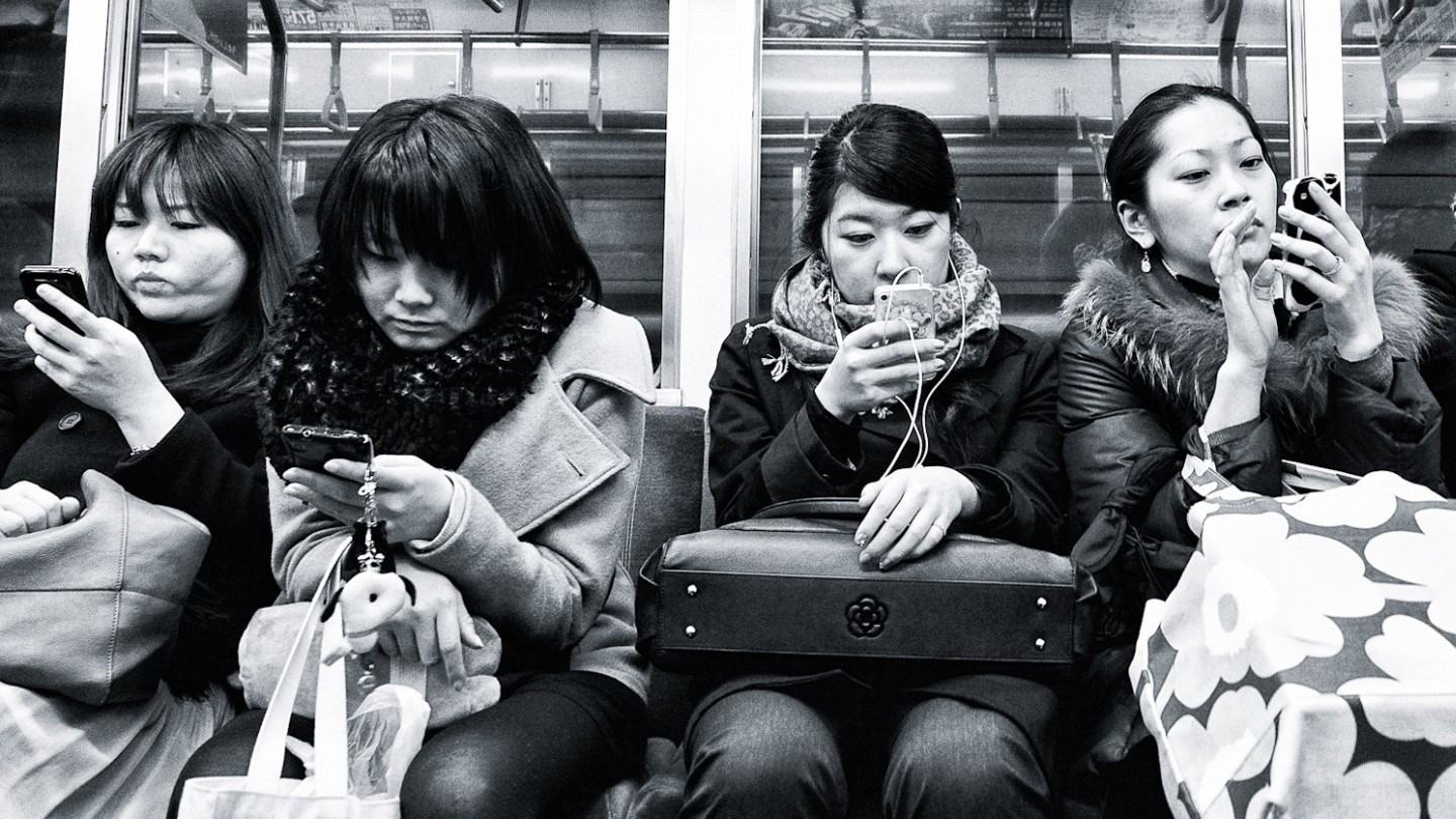 Taiwanesas mexendo no celular no metrô.