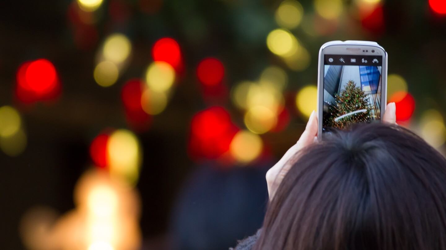 Mulher tirando foto da árvore de Natal.
