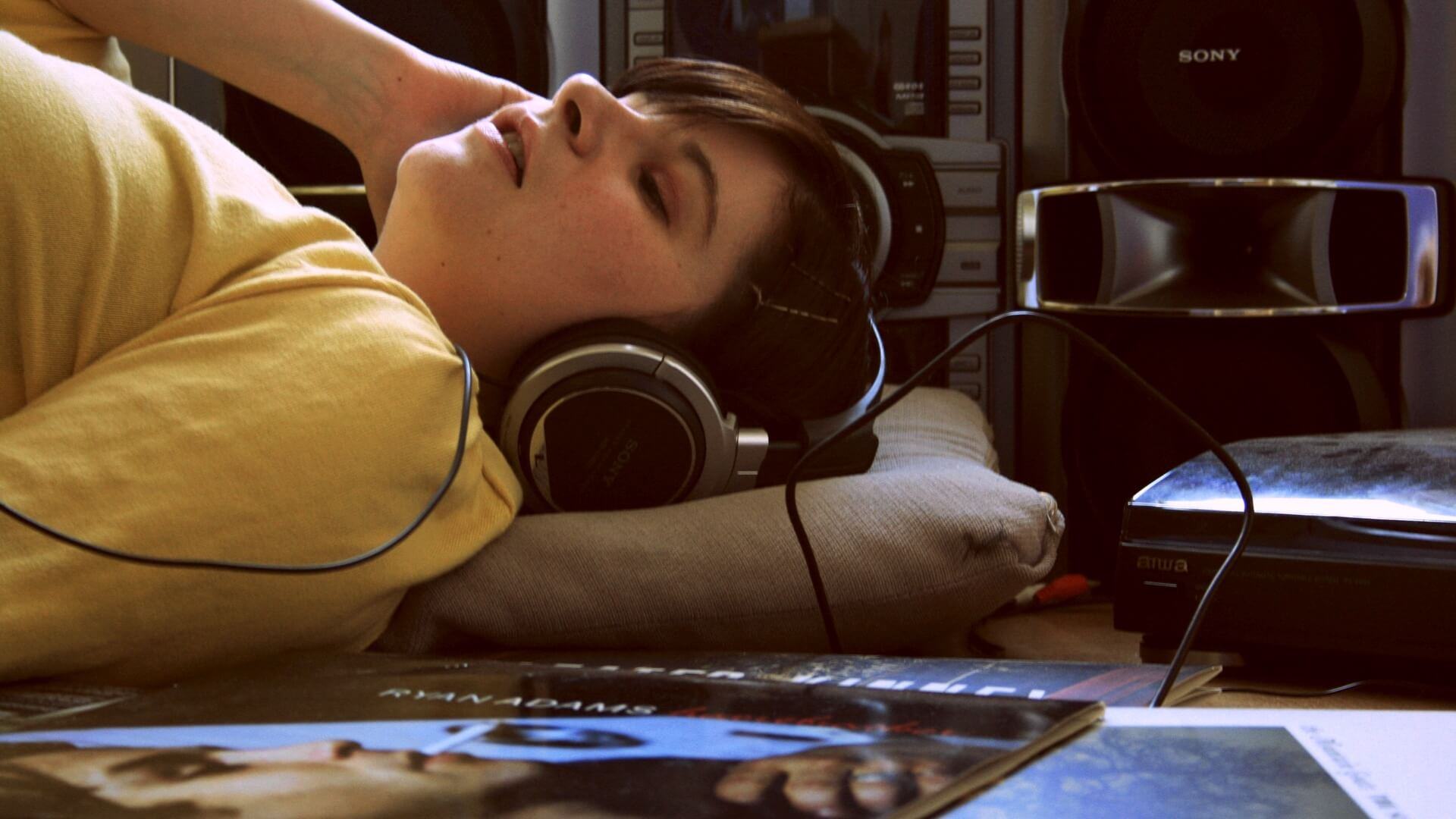 Mulher deitada ouvindo música em fones de ouvido.