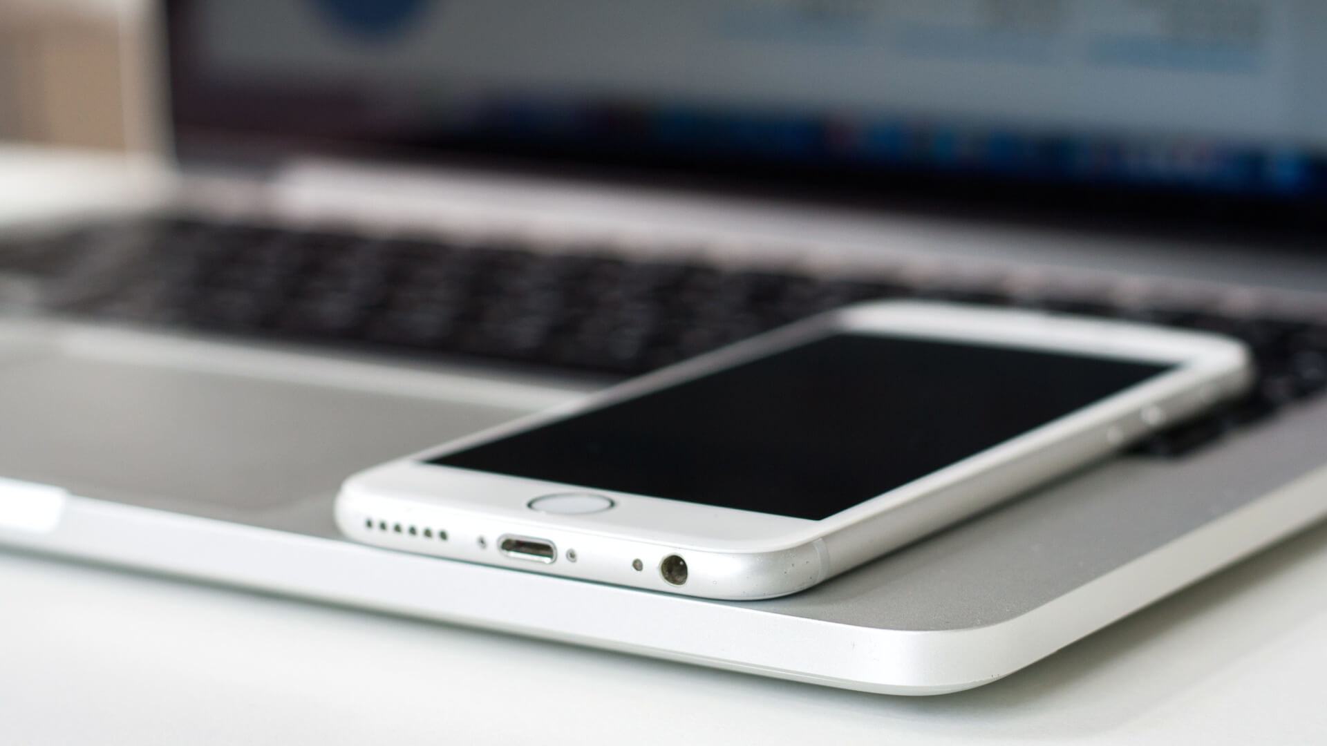 iPhone 6 ou 6s sobre um MacBook Pro aberto.