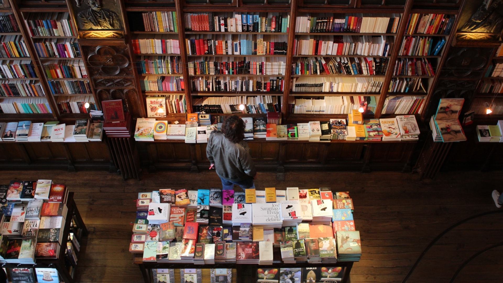 Homem entre prateleiras de uma livraria.