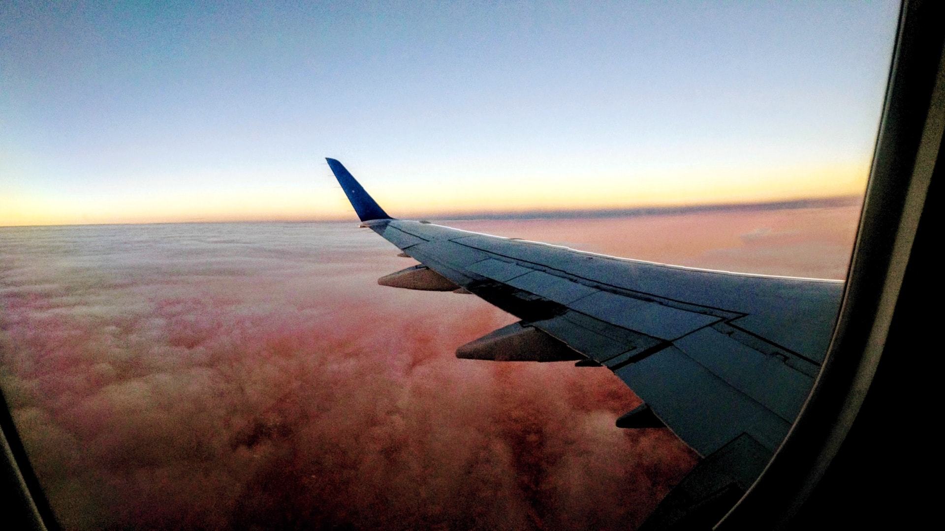 Foto da janela do avião ao entardecer.