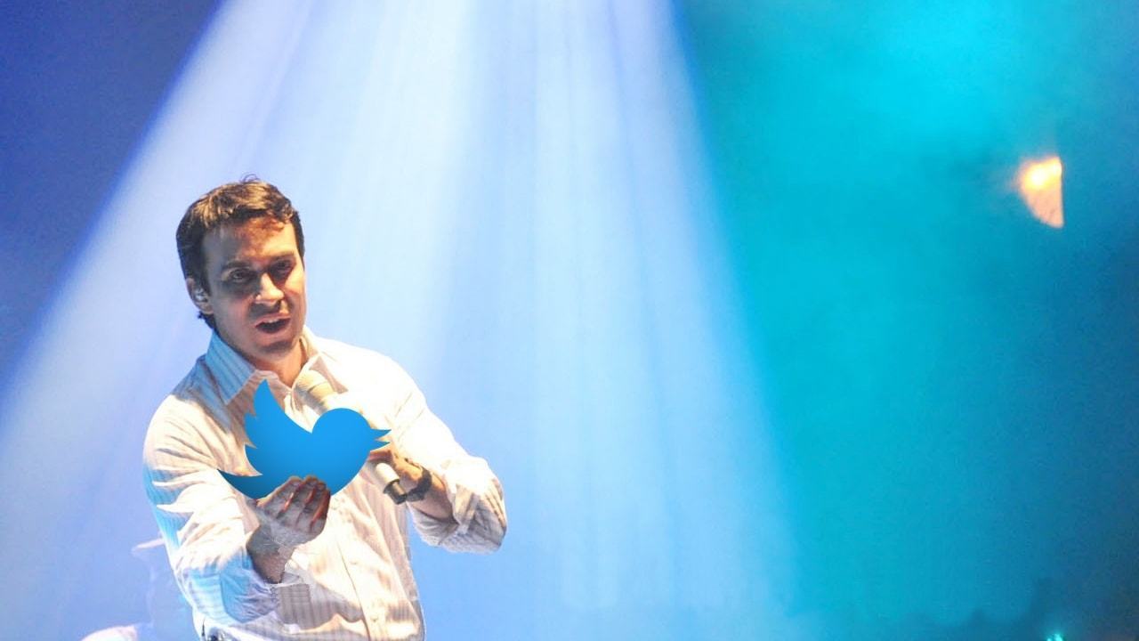 Montagem com o Pe. Fábio de Melo no palco segurando o pássaro (logo) do Twitter em uma das mãos.