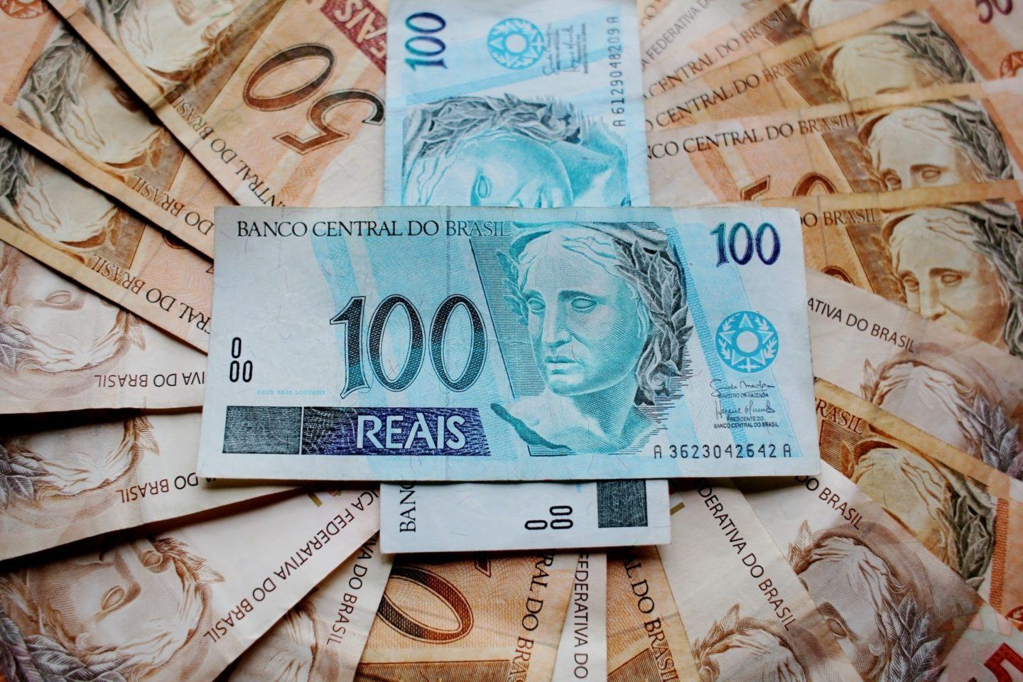Notas de R$ 50 espalhadas e duas de R$ 100 sobre elas.