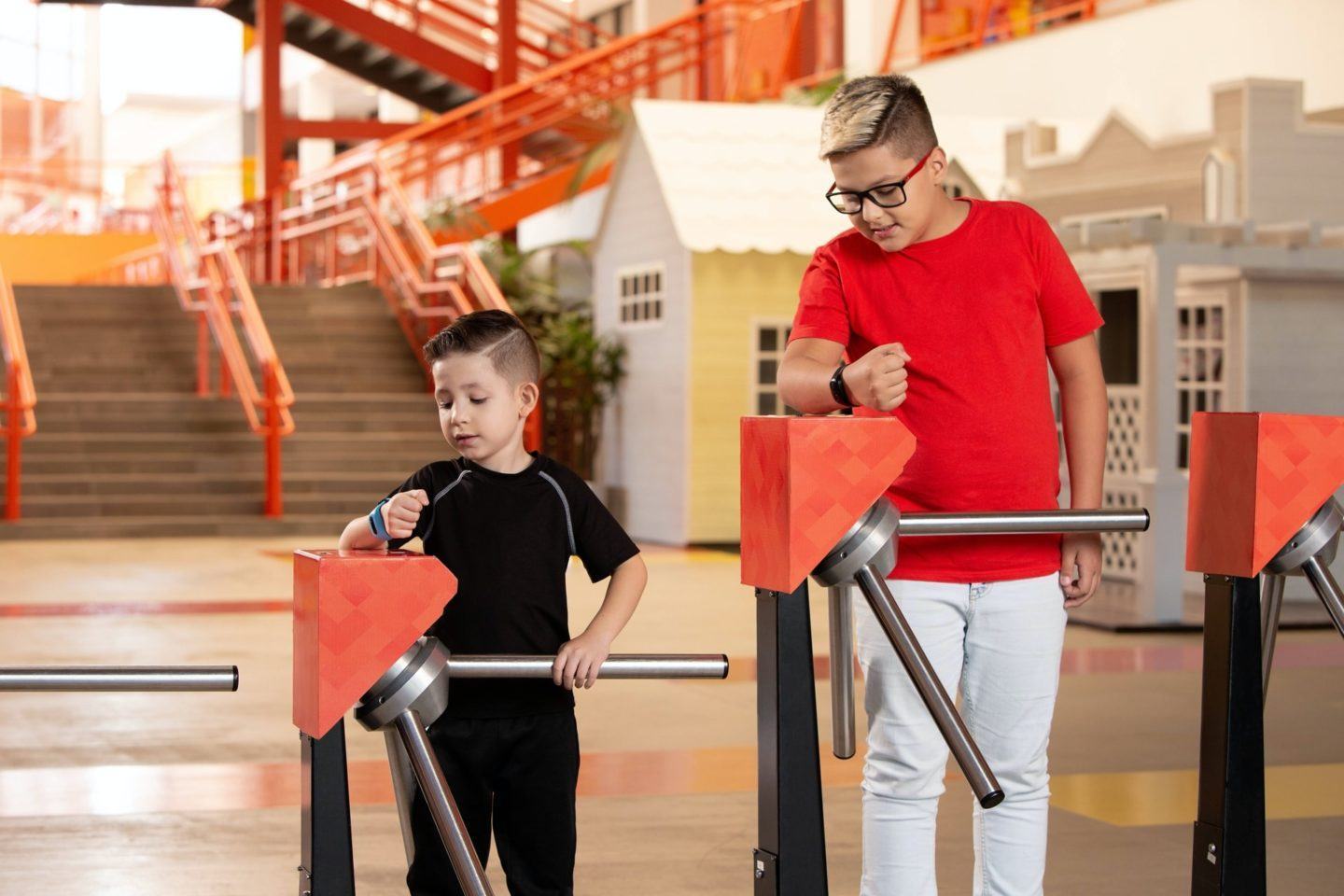 Duas crianças passando por catracas graças às suas pulseiras Schood.