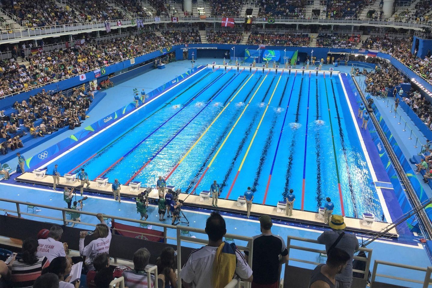 Piscina olímpica da Olimpíada do Rio de Janeiro, em 2016, vista de cima, com parte das arquibancadas aparecendo na foto.