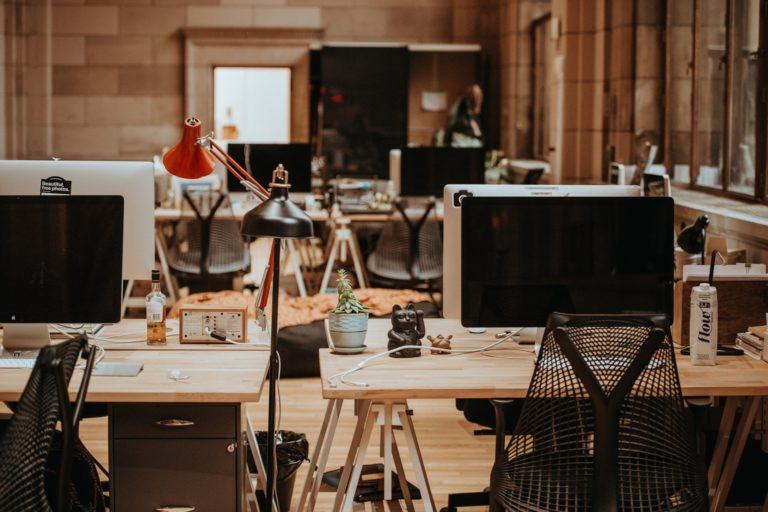 Um escritório moderno, com mesas e computadores, completamente vazio.