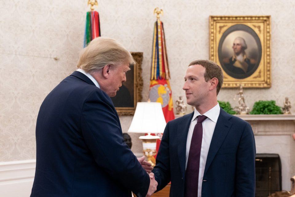 Trump, de costas, aperta a mão de Mark Zuckerberg no Salão Oval da Casa Branca.