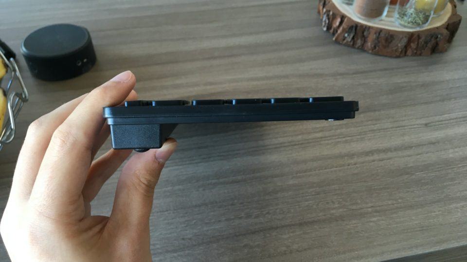 Teclado de perfil segurado por uma mão, mostrando sua espessura.