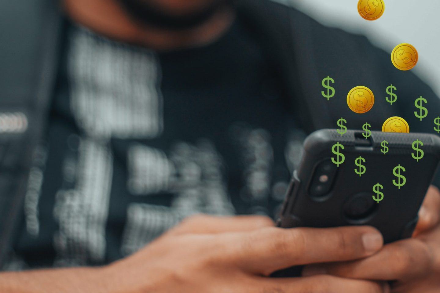 Detalhe de um celular na mão de um homem e, acima do celular, algumas moedinhas douradas e cifrões verdes caindo em direção a ele.