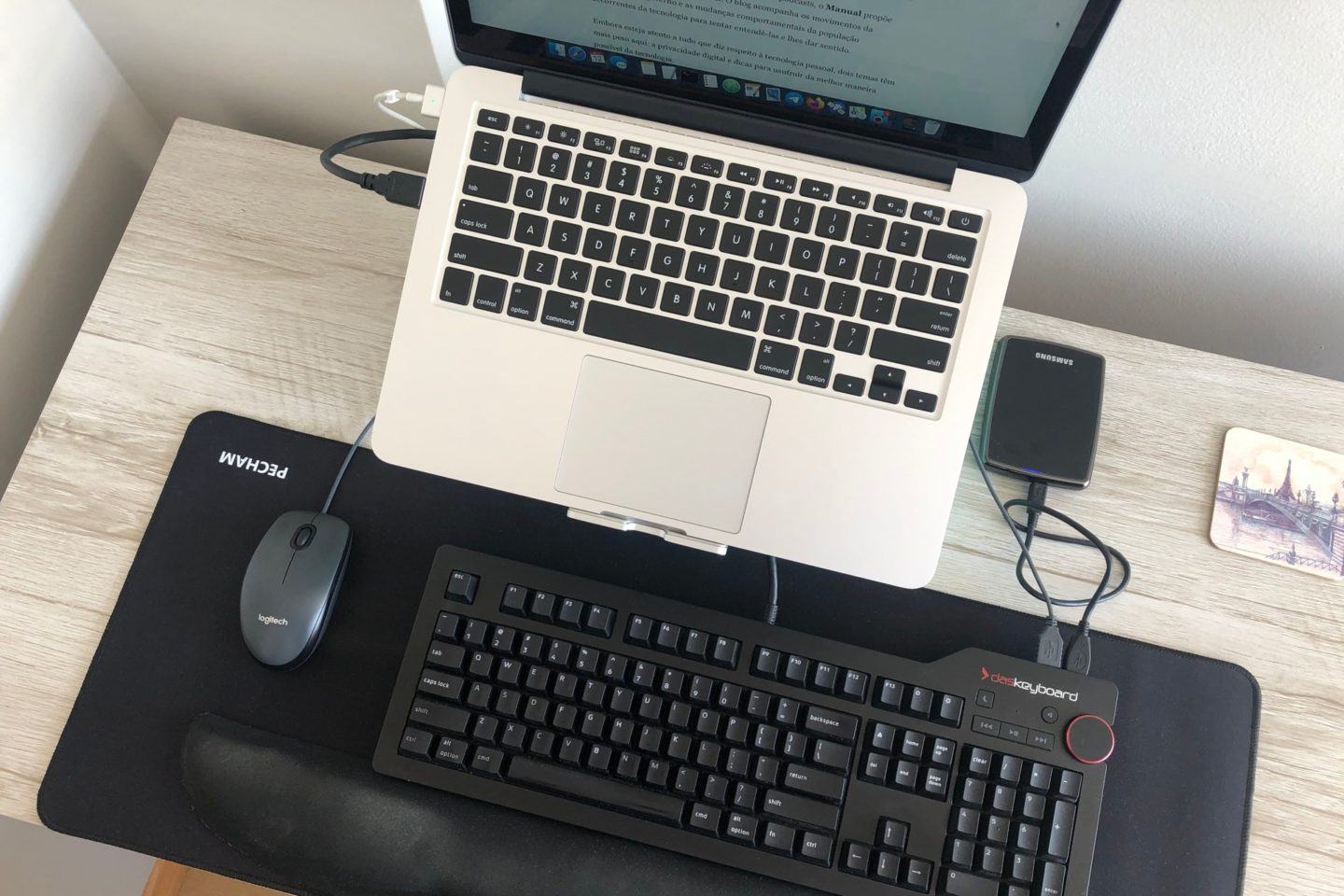 Foto de cima, mostrando teclados (do notebook e o mecânico), mouse, HD externo e mousepad.