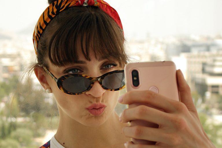 Mulher fazendo duckface ao tirar selfie.