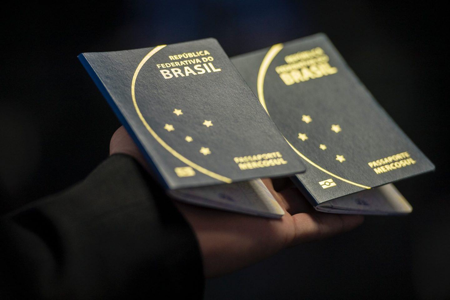 Dois passaportes brasileiros, o do Cruzeiro do Sul, segurados por uma mão.