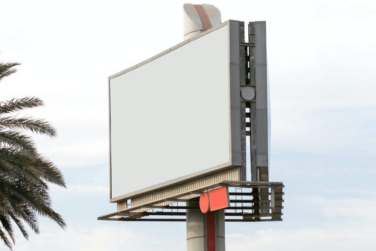 Outdoor branco em um poste; à esquerda, uma palmeira.