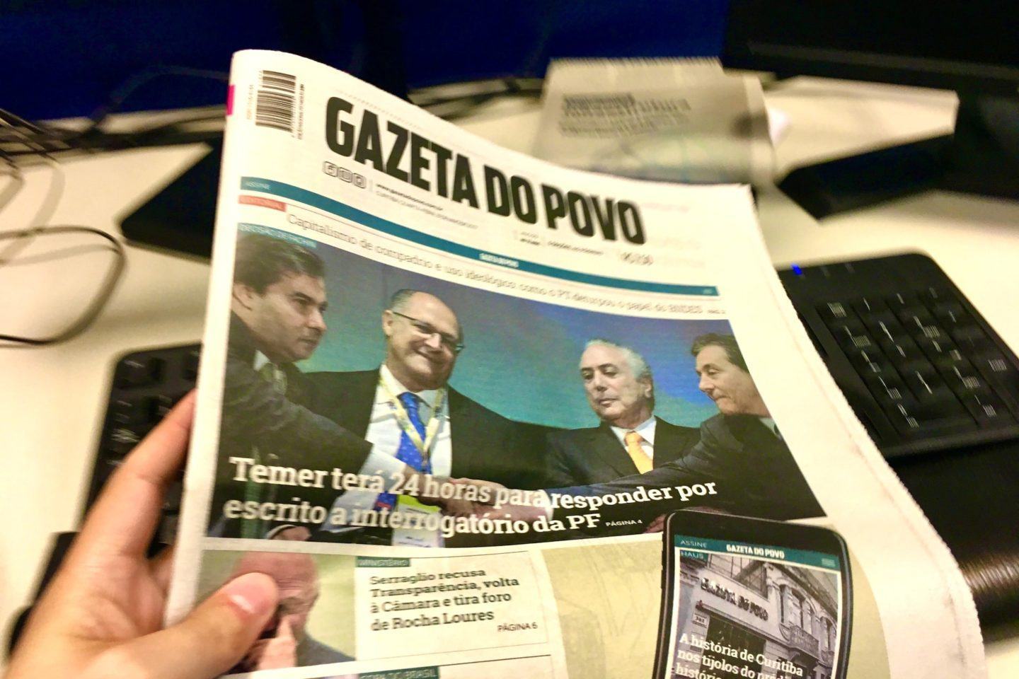 Foto de uma edição impressa da Gazeta do Povo segurada por uma mão.