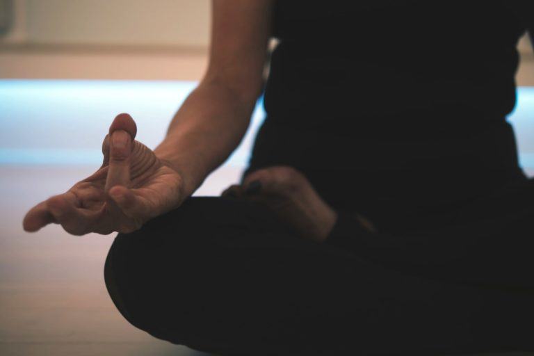 Detalhe na mão direita de uma pessoa, não identificada (a foto corta na altura do peito) praticando meditação.