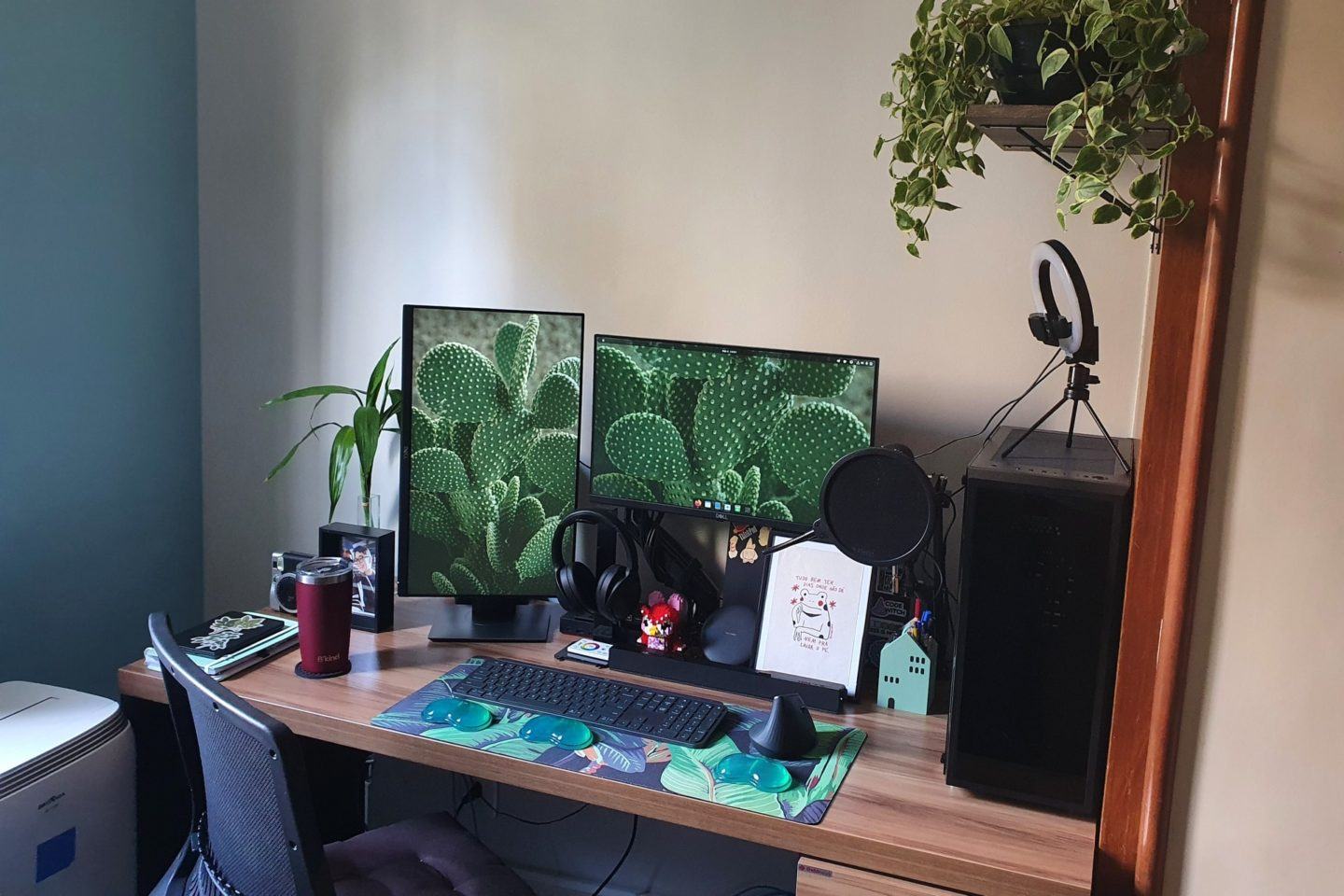 Mesa de escritório de madeira, com dois monitores, um deles na vertical, computador, ring light, mouse e teclado.