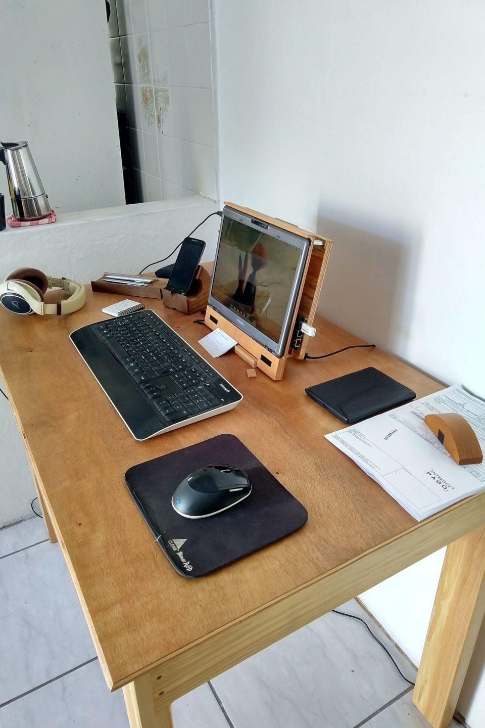 Foto, por outro ângulo, do escritório do Diego, com uma divisório em alvenaria ao fundo com uma garrafa térmica sobre ela.