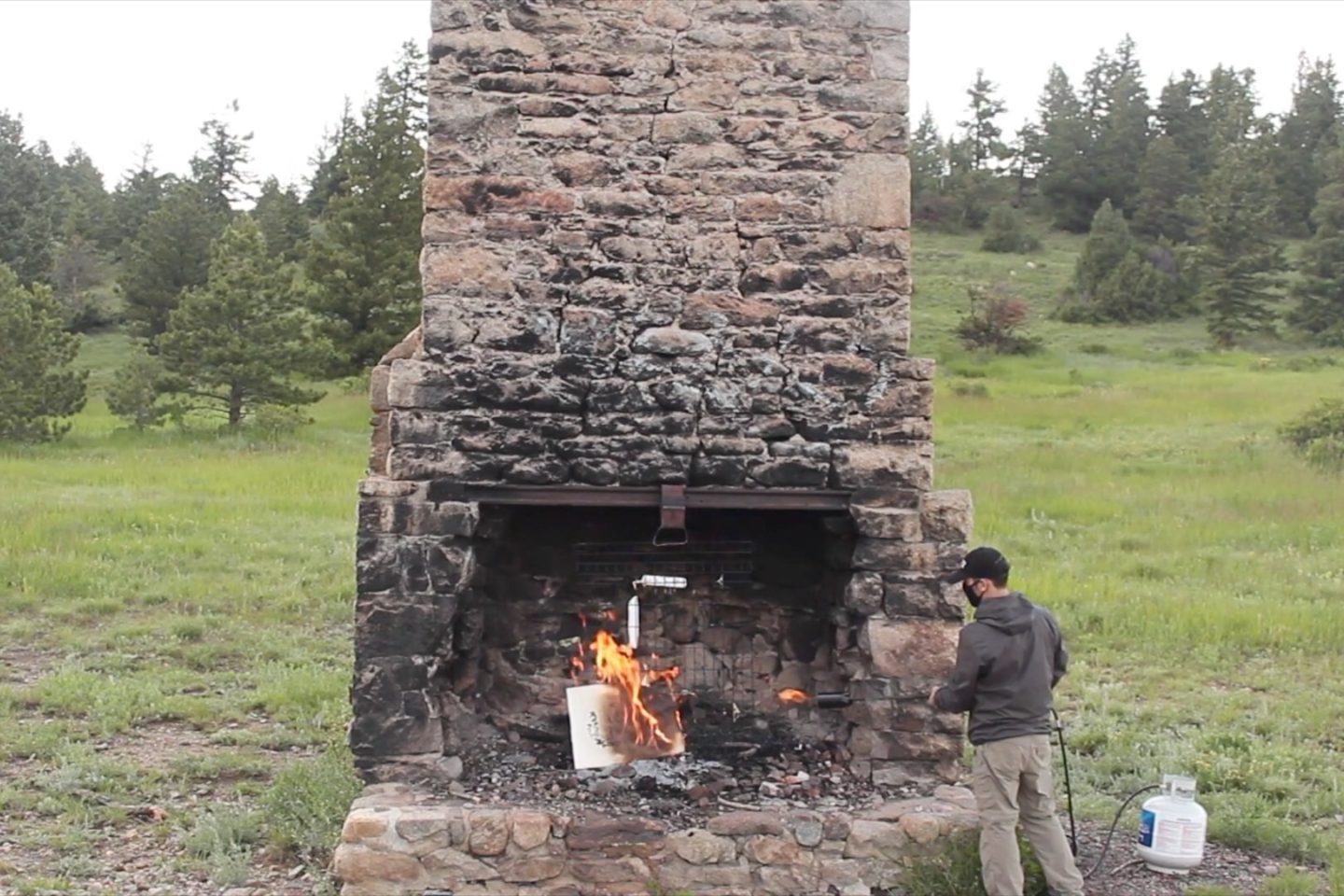 Lareira ao ar livre, com um original de Picasso em chamas. Ao lado, homem com um maçarico.