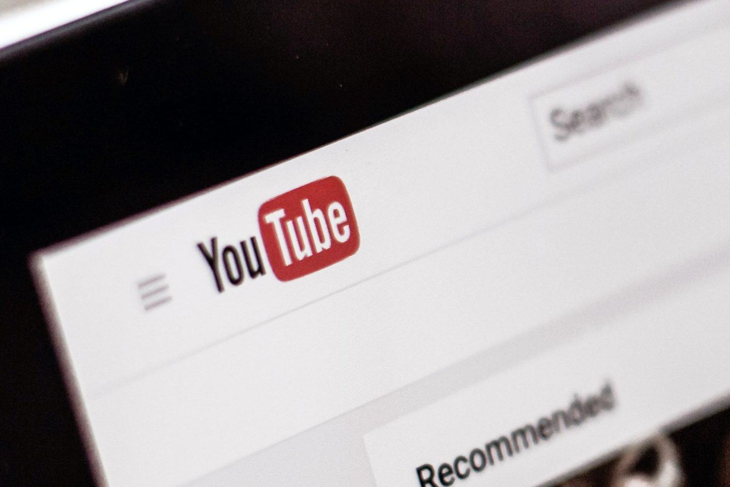 Foto em close do logo do YouTube no site, com a moldura da tela do notebook visível.