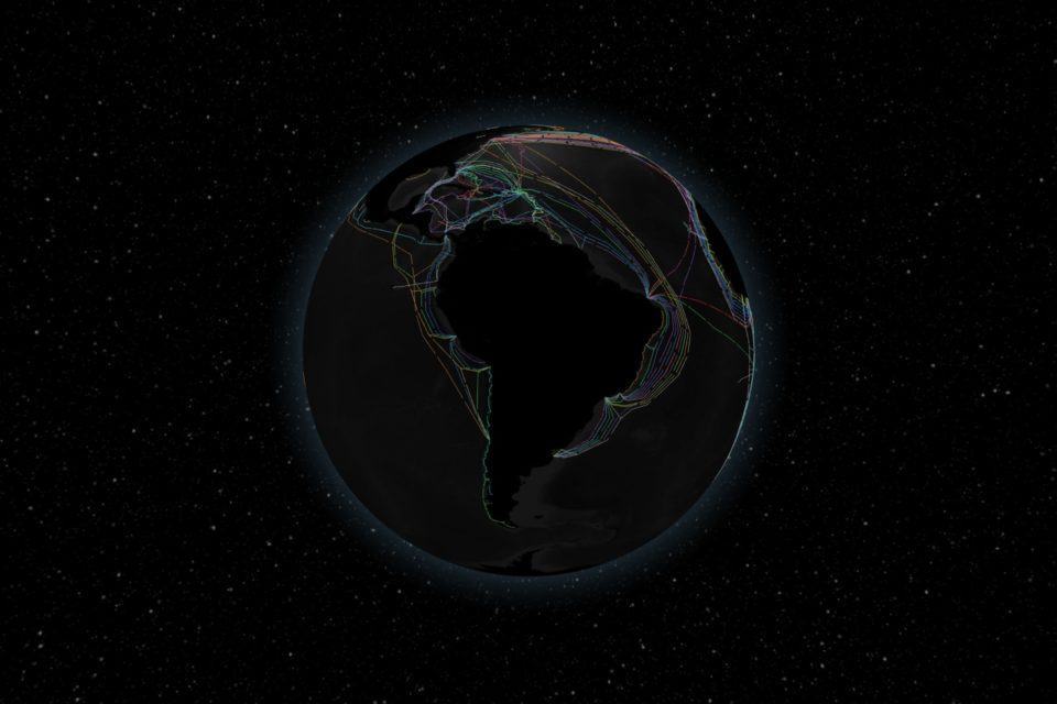 Globo terrestre, escuro, centralizado na América do Sul, com linhas nos oceans representando cabos submarinos de internet.