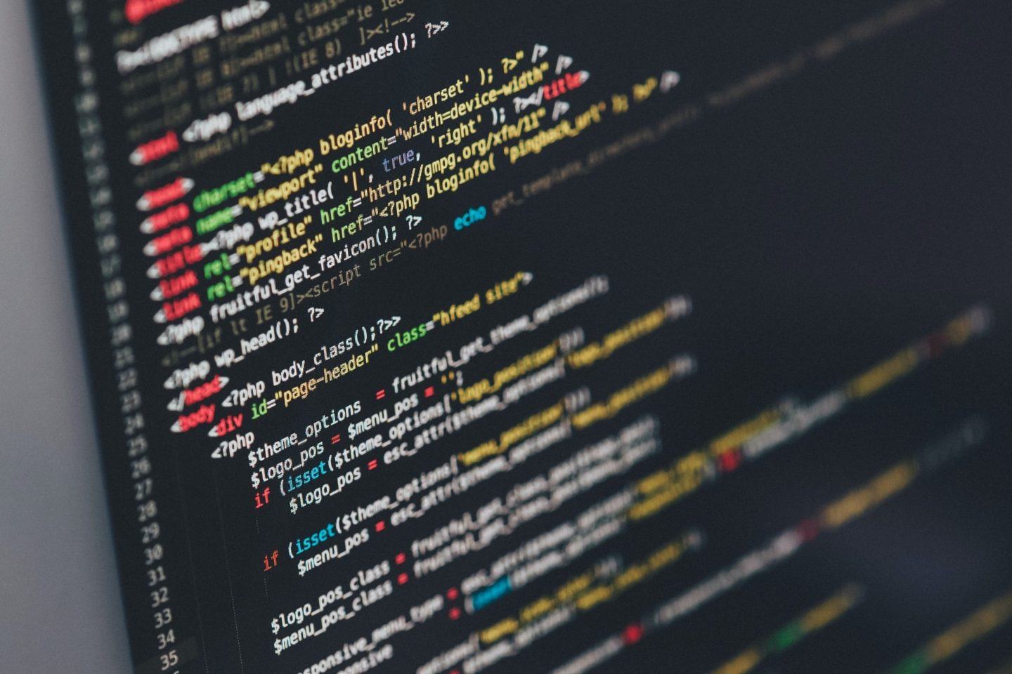 Foto de uma tela, com tema escuro, de um editor de HTML mostrando trechos do código-fonte de uma página.