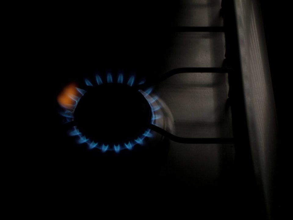 Foto de uma boca de fogão com a chama acesa, e uma pequena parte dela em cor alaranjada (o resto da chama é azul).