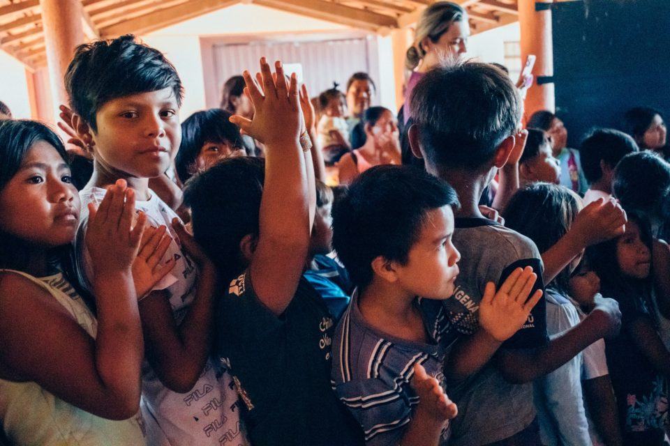 Várias crianças indígenas aglomeradas, algumas olhando para a câmera, outras, para frente.