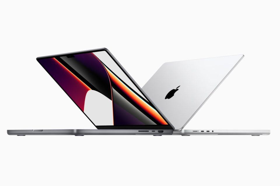 Dois MacBooks Pro novos, com as tampas semi-abertas, um de costas para o outro.