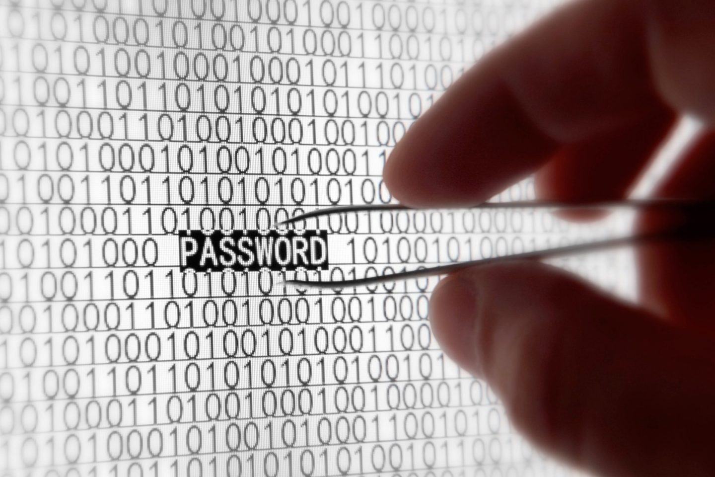 Mão com uma pinça colocada sobre a palavra “PASSWORD” em uma tela, destacada, em meio a incontáveis zeros e uns.
