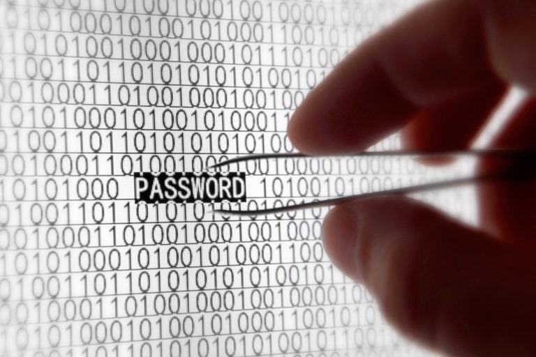 Mão com uma pinça colocada sobre a palavra “PASSWORD” em uma tela, destacada, em meio a incontáveis zeros e uns.