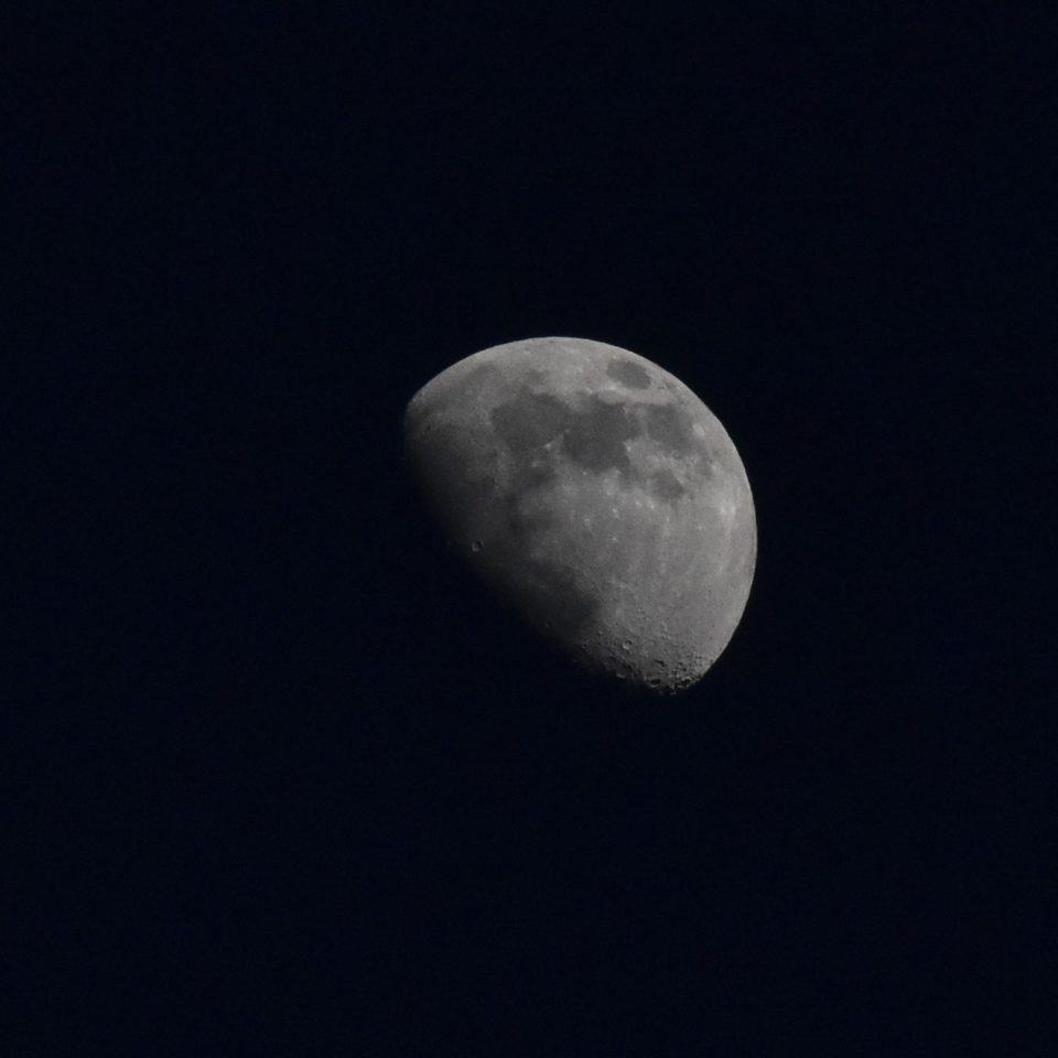 Foto da Lua, aparentemente em preto e branco, com sombra parcial.