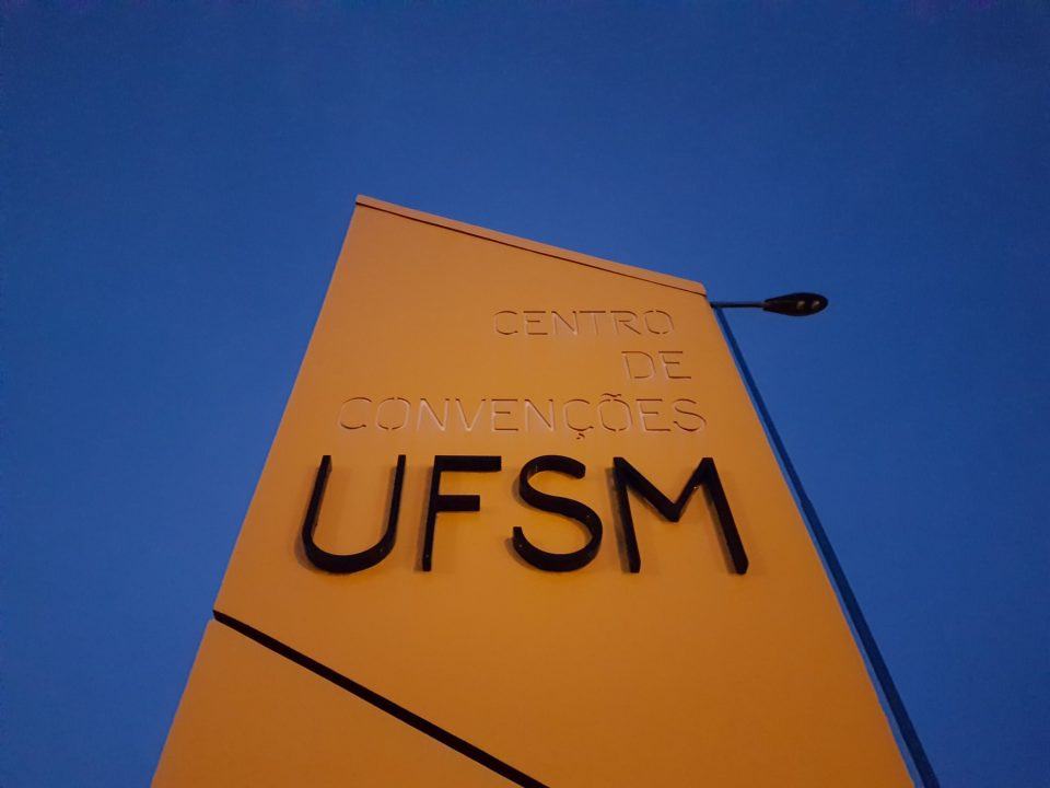 Foto de baixo para cima, de uma placa de concreto escrito “Centro de Convenções UFSM”.