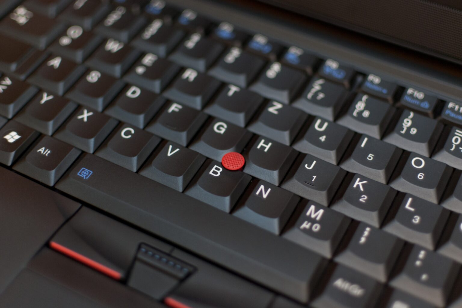 Foto no detalhe de um teclado de notebook ThinkPad L412, destacando o trackpoint (bolinha vermelha).