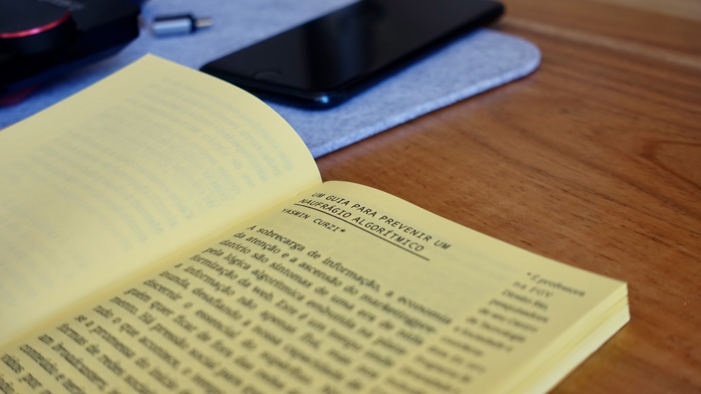 Foto em close do título do prefácio e nome da Yasmin Curzi. Ao fundo, desfocados, pen drive e celular.