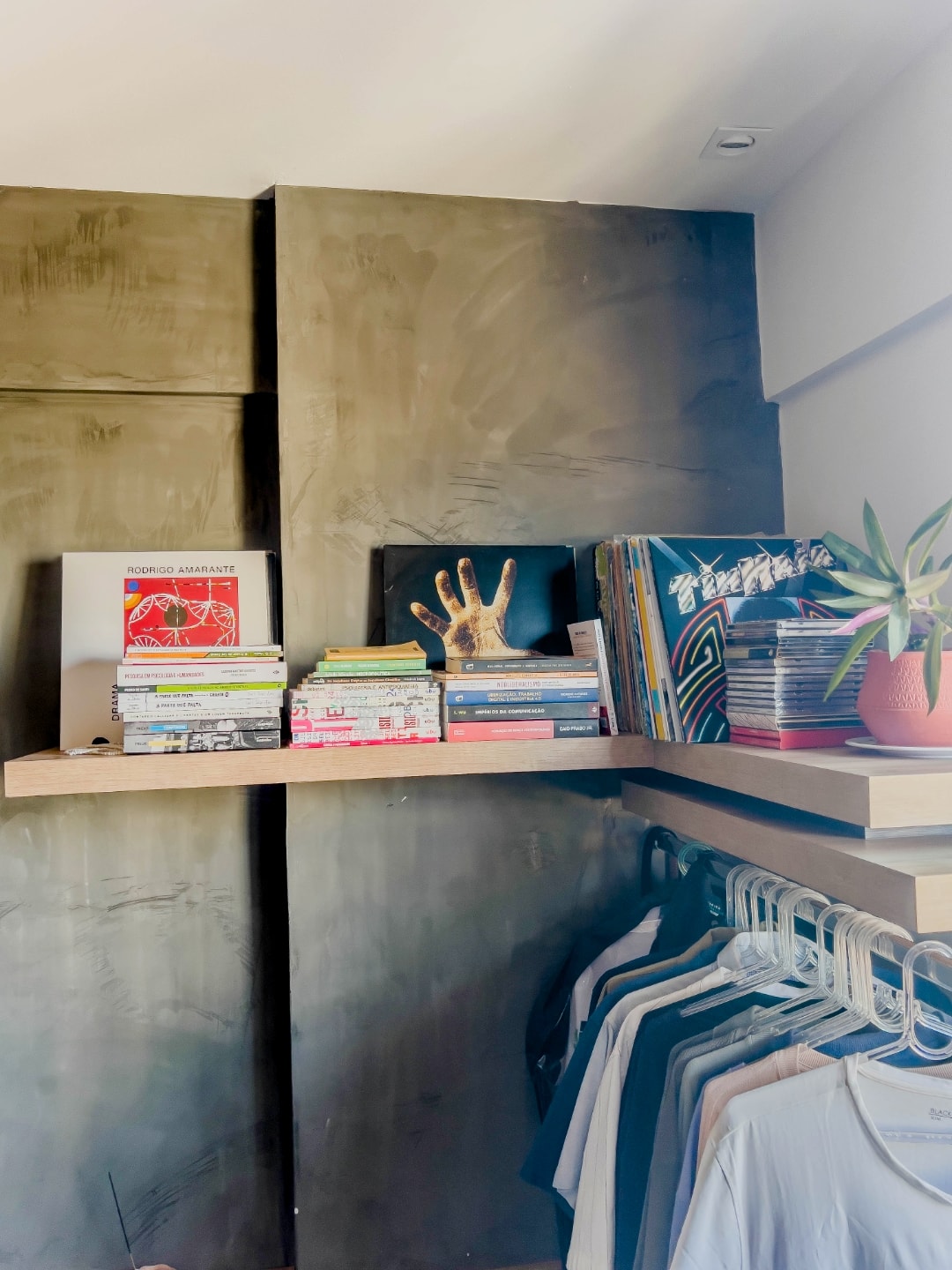 Prateleira única, em “L”, com vinis e livros.