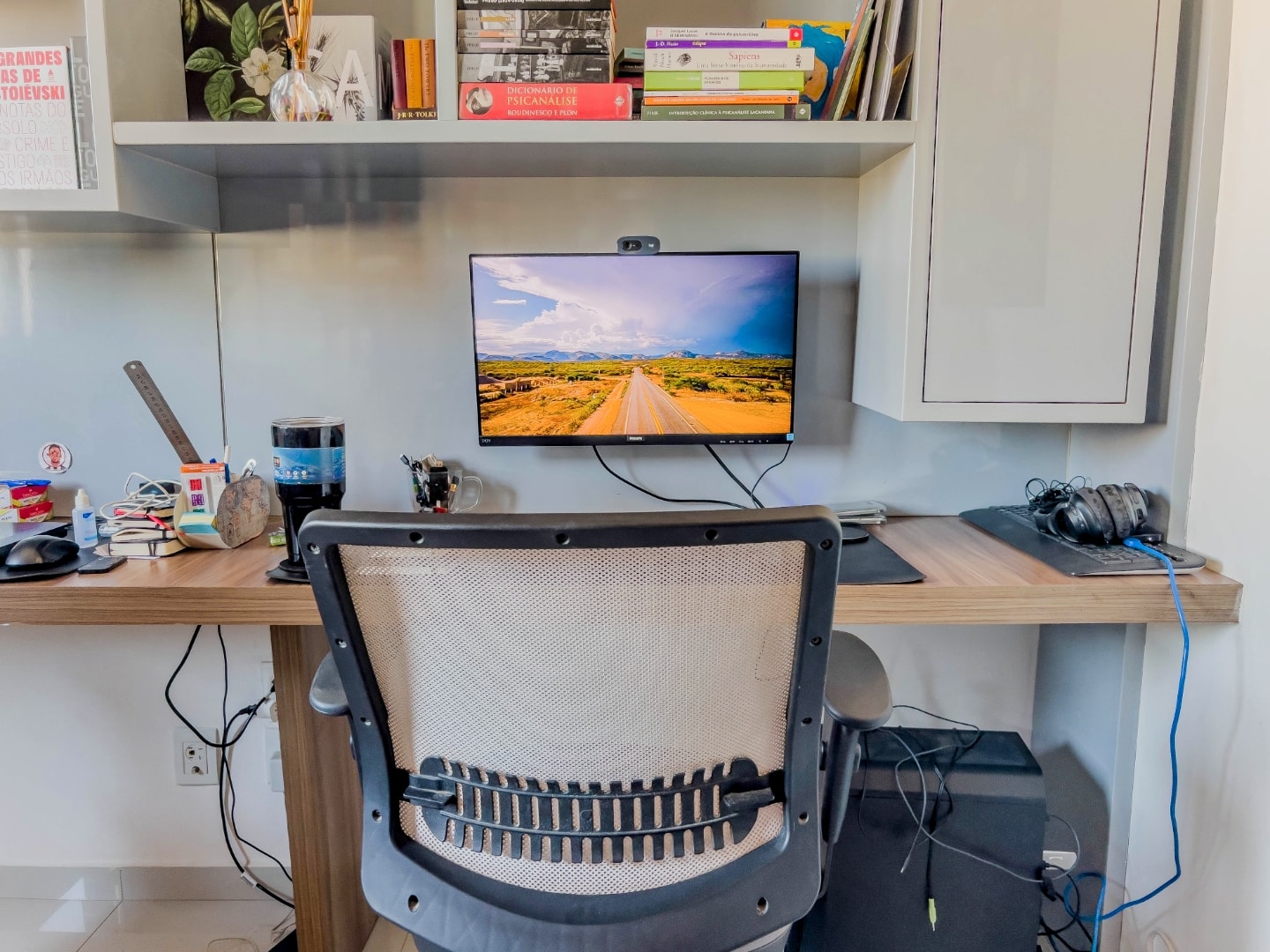Foto frontal da mesa de trabalho do Caiubi, mostrando a cadeira, monitor e alguns acessórios.