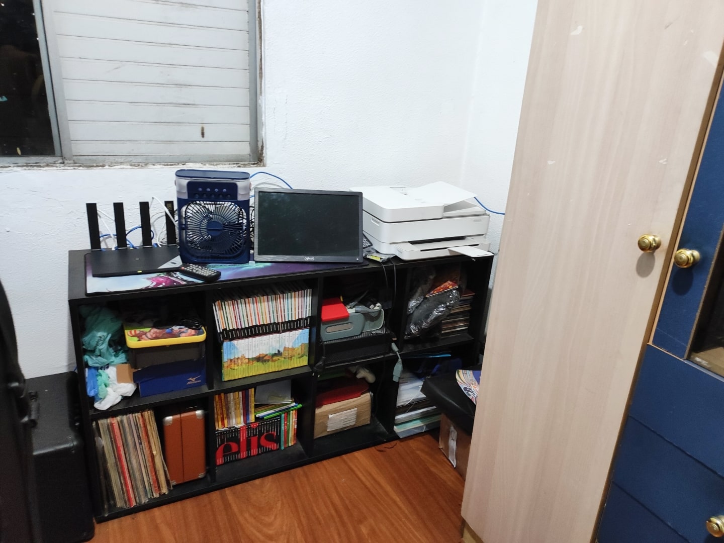 Detalhes da mesa secundária, com impressora branca e roteador preto.