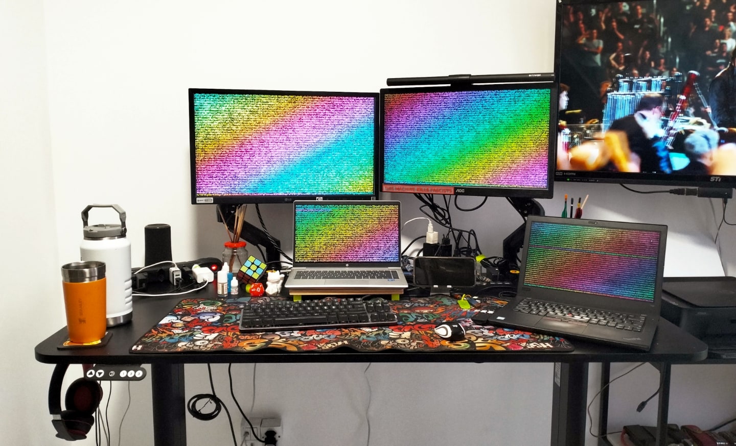 Foto frontal da mesa de trabalho do Carlos, destacando os monitores e notebooks.