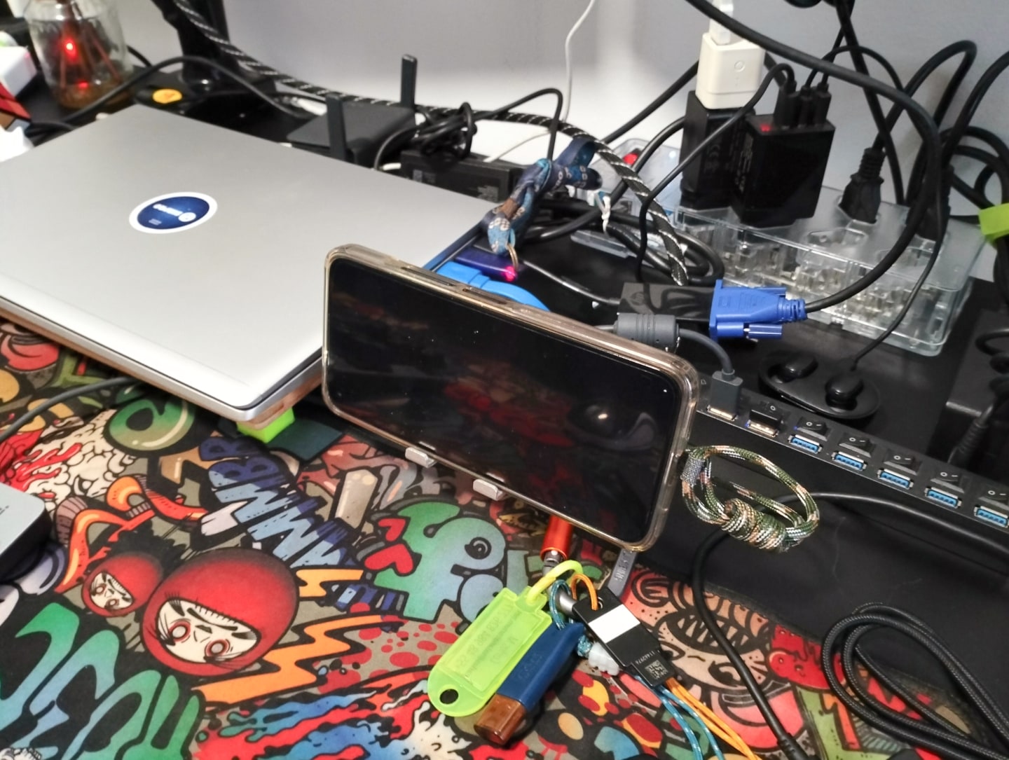 Celular, notebook fechado e diversos pequenos acessórios sobre a mesa.