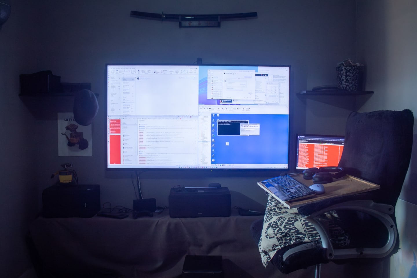 Foto de frente da mesa de trabalho, com TV grande ao centro, em destaque.