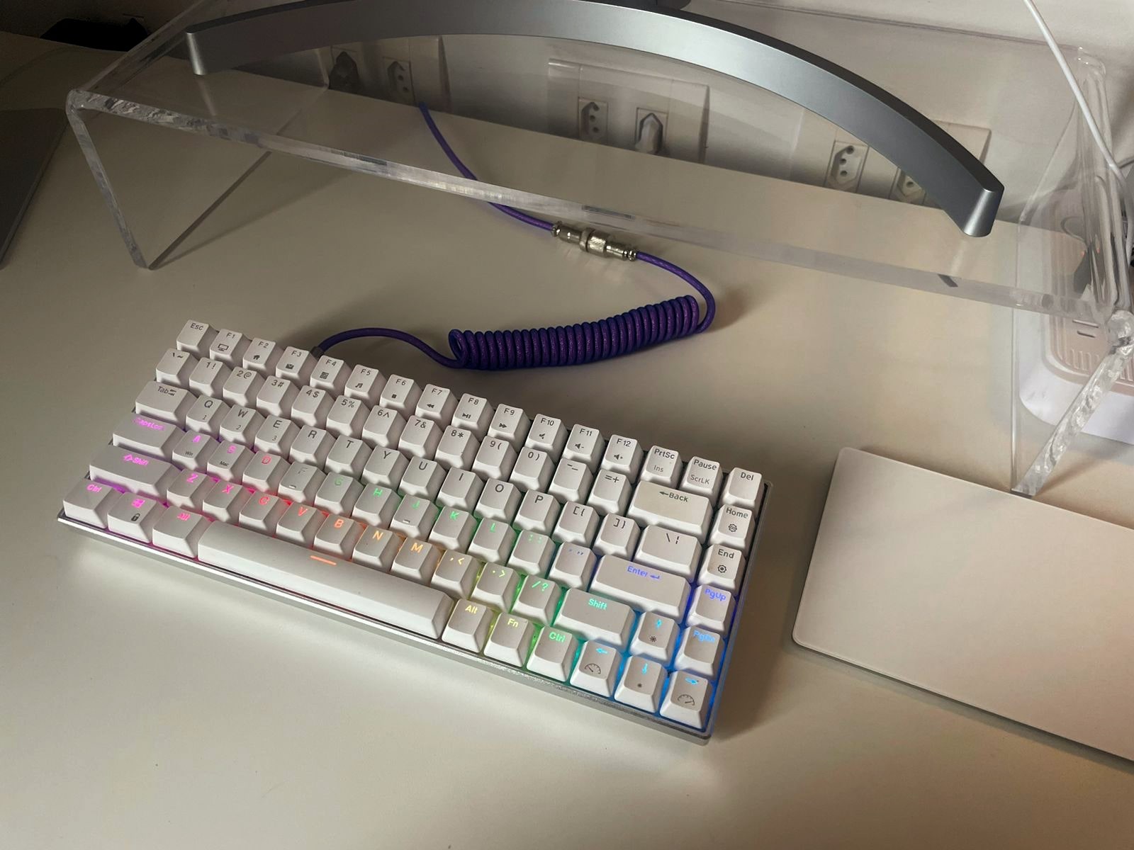 Teclado branco, de teclas altas, com um cabo tipo de telefone antigo na cor roxa.