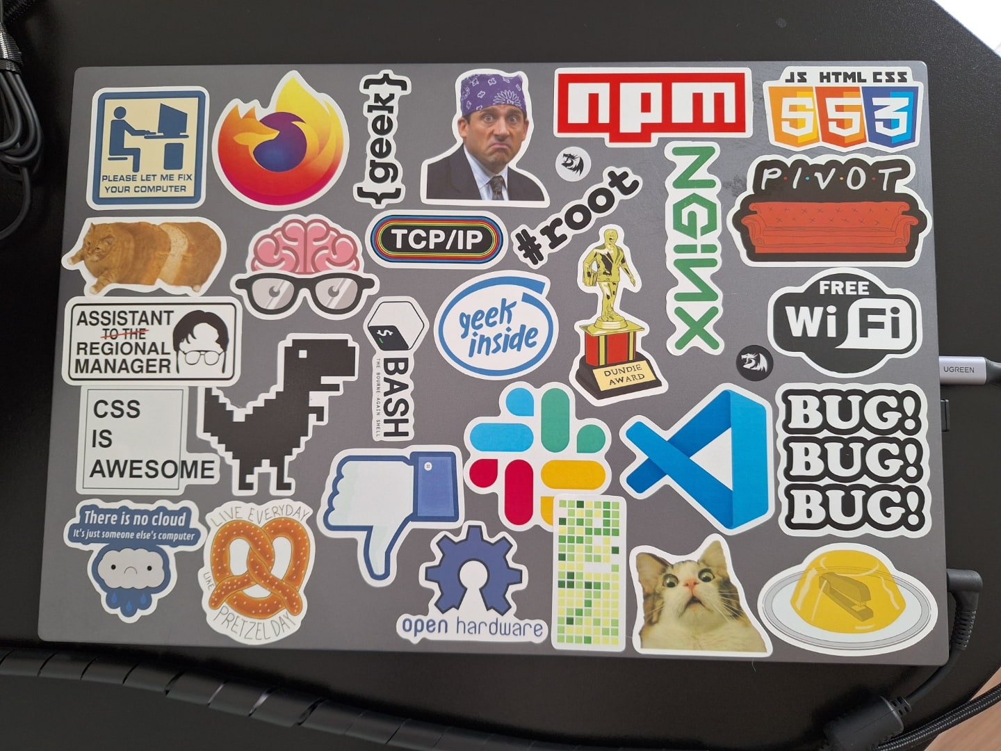 Tampa de um notebook prata repleta de adesivos.