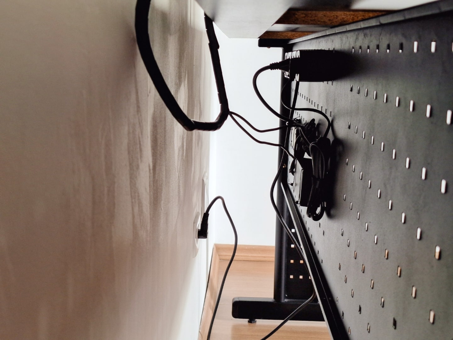 Vão da mesa e a parede, com cabos organizados em uma grelha afixada à mesa.