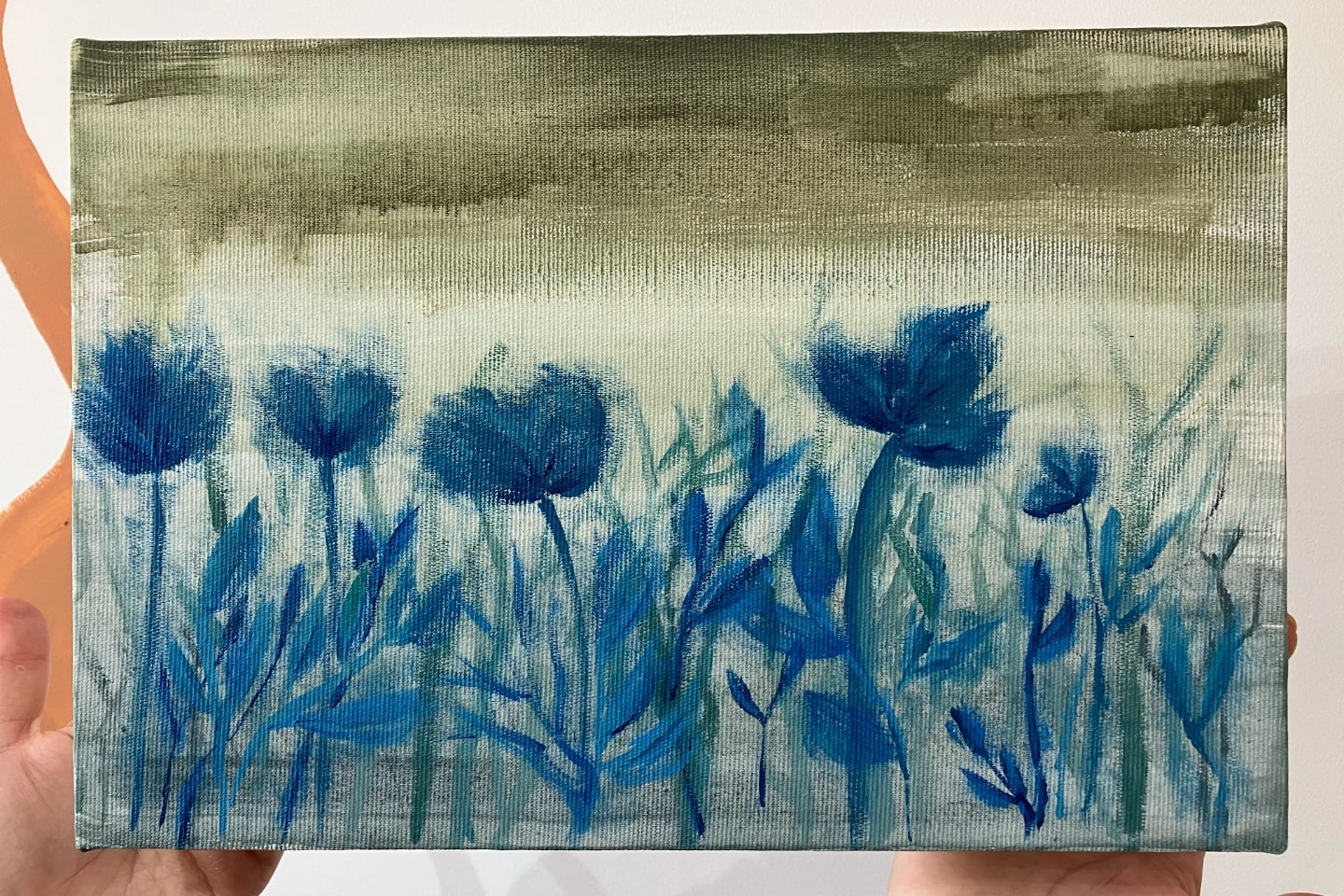 Plantas azuis, com flores borradas, em primeiro plano, e fundo meio verde oliva em degradê.