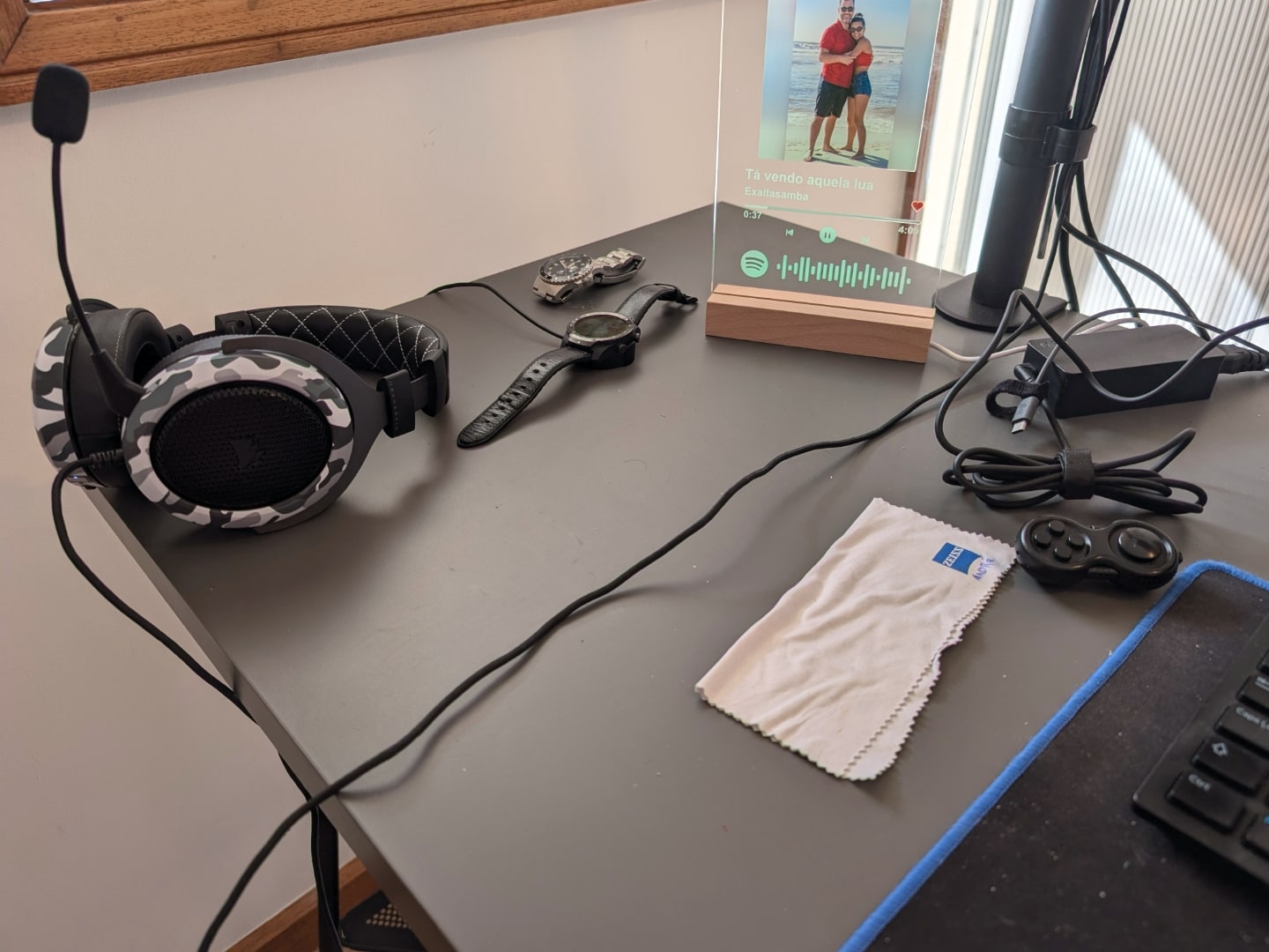 Detalhe da mesa com alguns objetos — headset, relógios, porta-retratos.